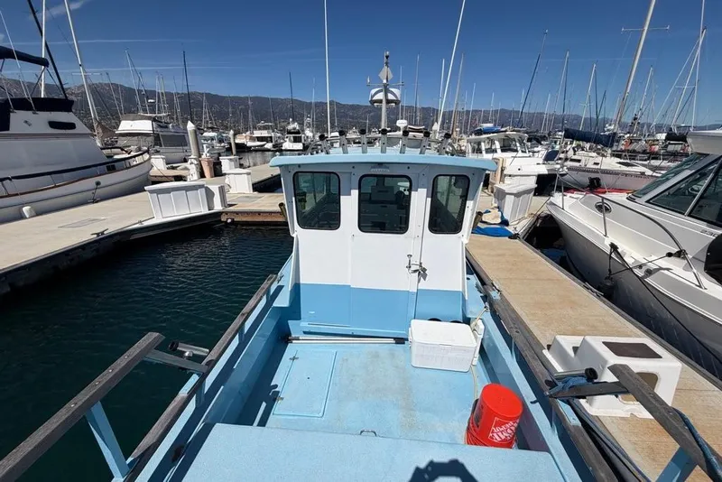 Slide: The Image of 1976 Wilson 24 boat docked at a marina with surrounding yachts. - 6