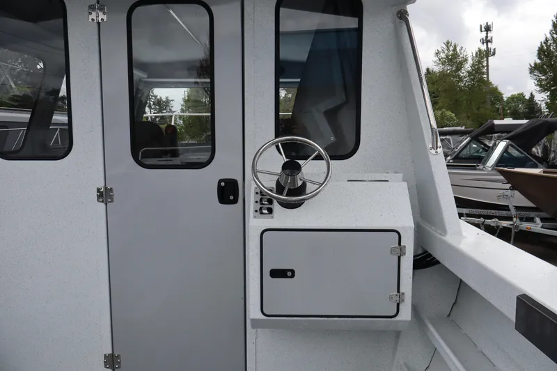 Slide: The Image of 2026 KingFisher 2825 Coastal Express boat exterior with steering wheel and cabin door. - 11