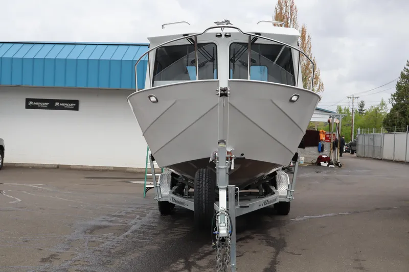 Slide: The Image of 2026 KingFisher 2825 Coastal Express boat on trailer, parked outdoors near blue-roofed building. - 5