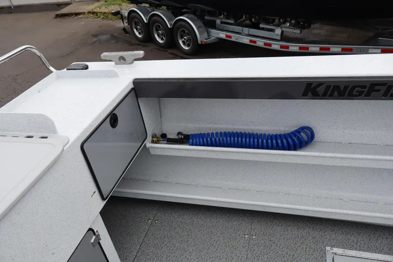 Slide: The Image of 2026 KingFisher 2825 Coastal Express boat interior with storage compartment and blue hose. - 9