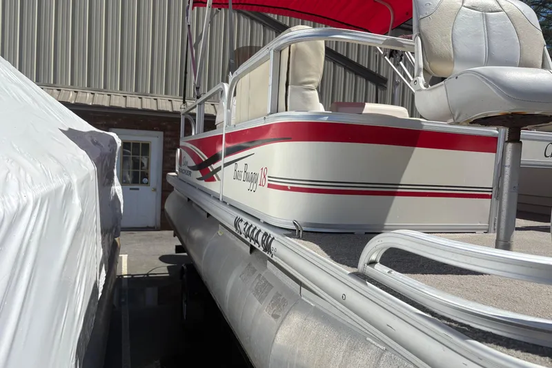 The Image of 2011 Sun Tracker Bass Buggy 18 Classic pontoon boat with red accents, parked outdoors. - 0