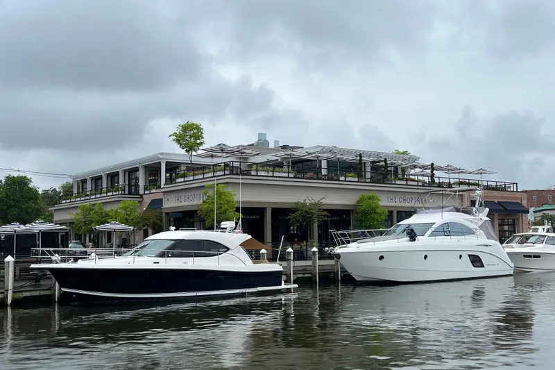 Slide: The Image of Beneteau Monte Carlo 47 Fly yacht docked near waterfront restaurant, cloudy sky. - 13