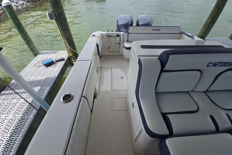 Slide: The Image of 2012 Contender 32 LS boat interior with cushioned seating and twin engines at dock. - 19