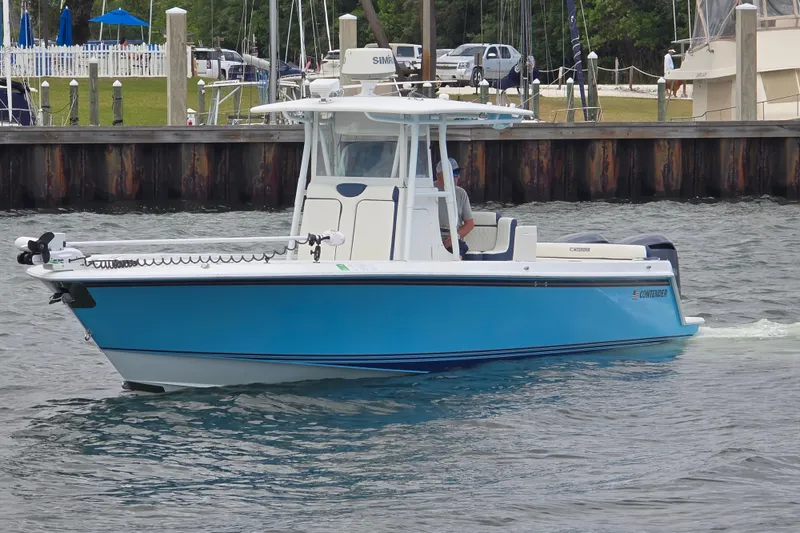 Slide: The Image of 2012 Contender 32 LS boat cruising near a marina, featuring a sleek blue design. - 2