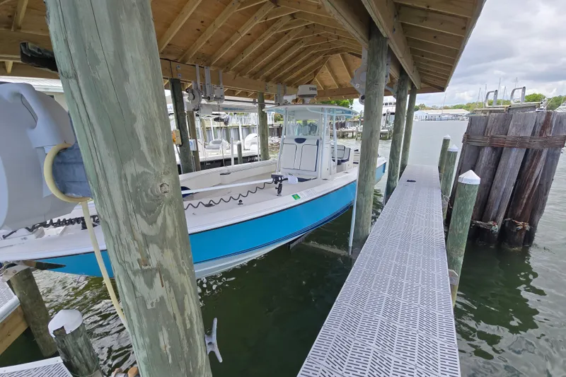 Slide: The Image of 2012 Contender 32 LS boat docked under a wooden shelter by the water. - 21