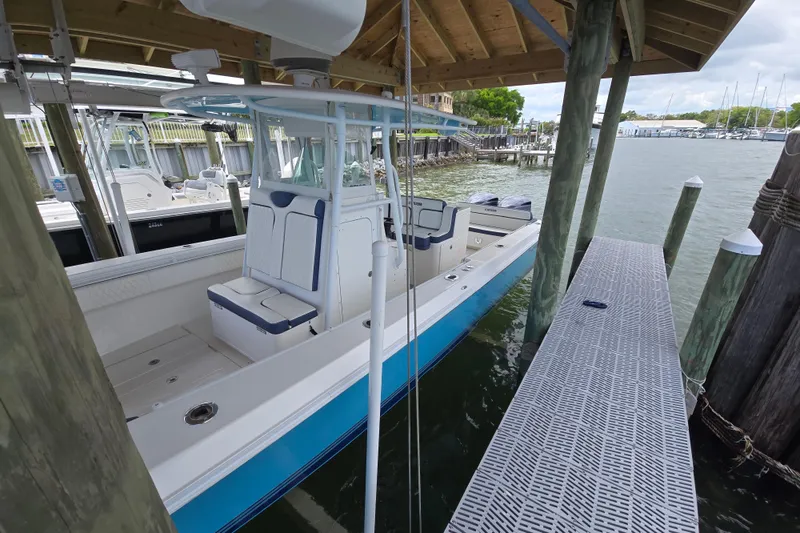 Slide: The Image of 2012 Contender 32 LS boat docked under a wooden shelter by the water. - 22