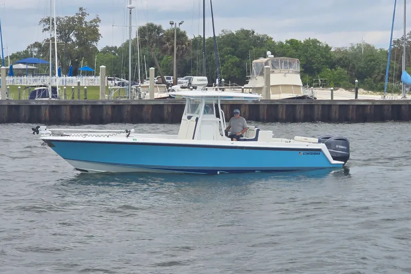 Slide: The Image of 2012 Contender 32 LS boat on water near marina, featuring Yamaha engines. - 3