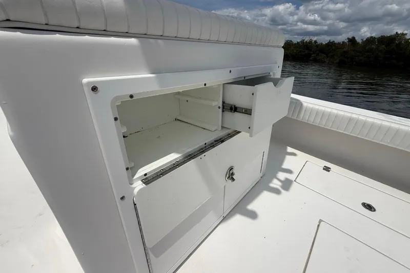 Slide: The Image of Open storage compartment on a 2016 Dorado 25 SE boat, with white cushioned seating. - 25
