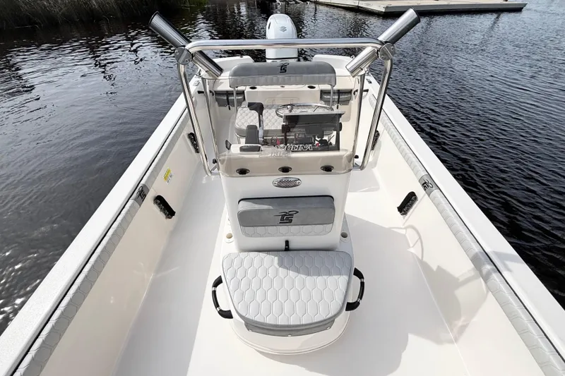 Slide: The Image of 2025 Carolina Skiff 21LS boat interior with console and seating, docked on calm water. - 10