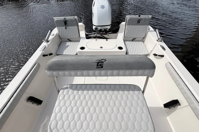 Slide: The Image of 2025 Carolina Skiff 21LS boat interior with cushioned seating and motor on water. - 11