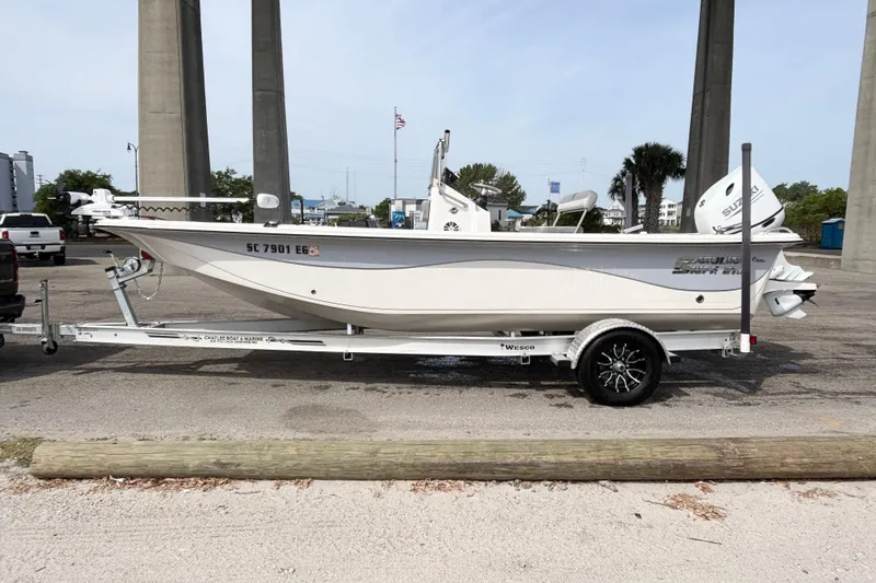 Slide: The Image of 2025 Carolina Skiff 21LS boat on trailer, parked outdoors near bridge. - 16