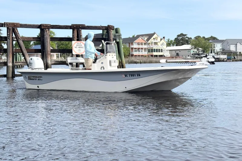 Slide: The Image of 2025 Carolina Skiff 21LS boat on calm water near dockside homes. - 3