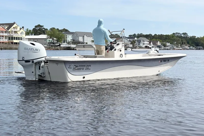 Slide: The Image of 2025 Carolina Skiff 21LS boat with Suzuki engine on calm water near residential area. - 5