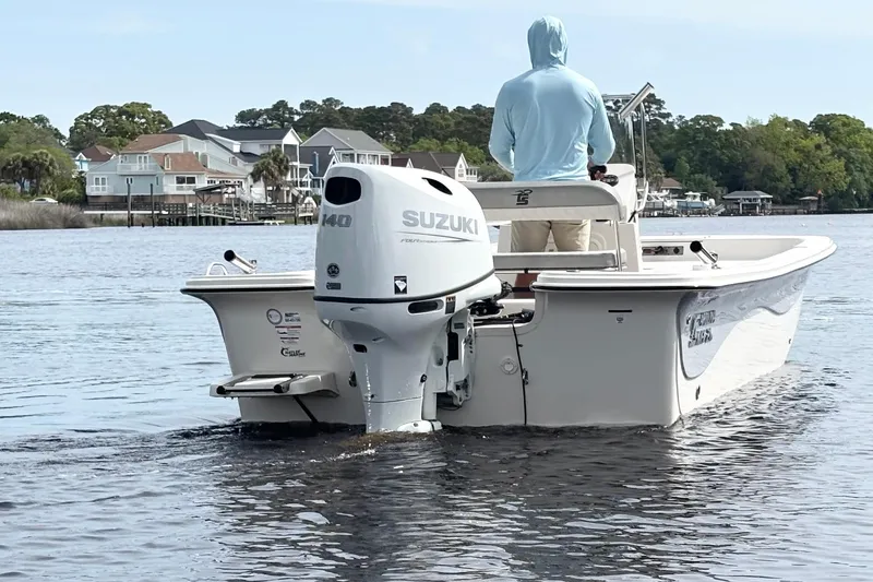 Slide: The Image of 2025 Carolina Skiff 21LS boat with Suzuki engine on calm water, near waterfront homes. - 6