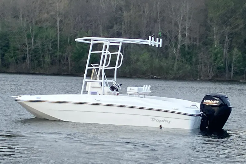 Slide: The Image of 2026 Bayliner Trophy T18 boat on a calm lake with forested background. - 2