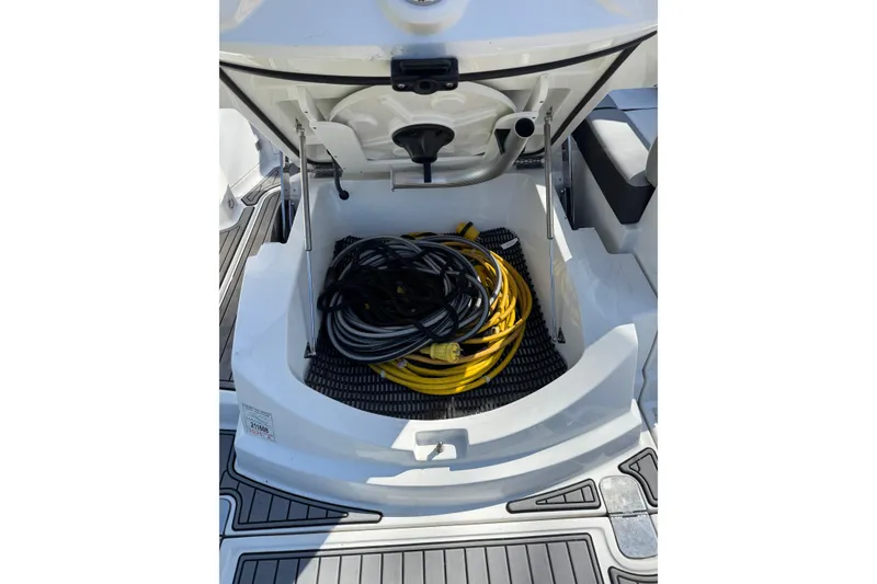 Slide: The Image of Open storage compartment on 2021 Monterey 295 Sport Yacht with coiled cables inside. - 18