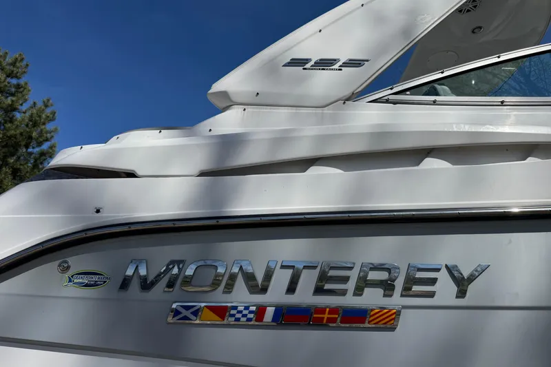 Slide: The Image of 2021 Monterey 295 Sport Yacht with nautical flags, sleek design, and clear blue sky. - 3