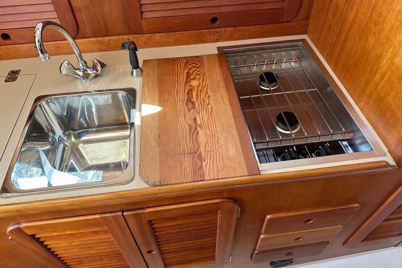 Slide: The Image of Hinckley Picnic Boat 36 Classic 1996 galley with sink and stove, featuring wooden cabinetry. - 14