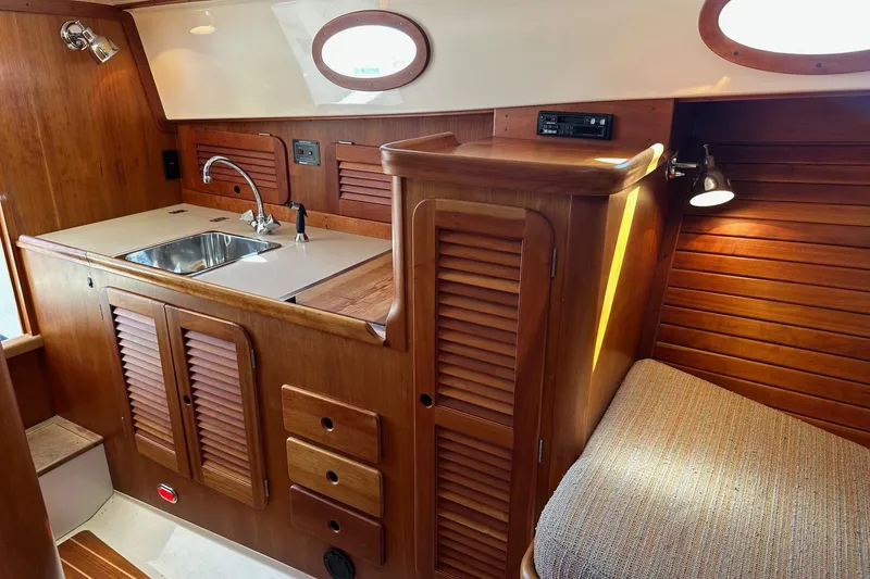 Slide: The Image of Interior of 1996 Hinckley Picnic Boat 36 Classic with wooden cabinetry and compact sink area. - 15