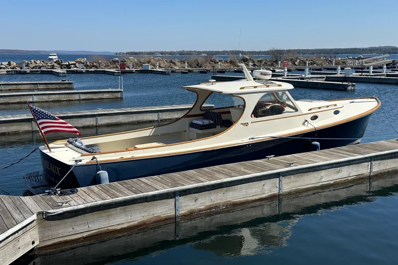 Slide: The Image of 1996 Hinckley Picnic Boat 36 Classic docked at a marina with an American flag. - 2
