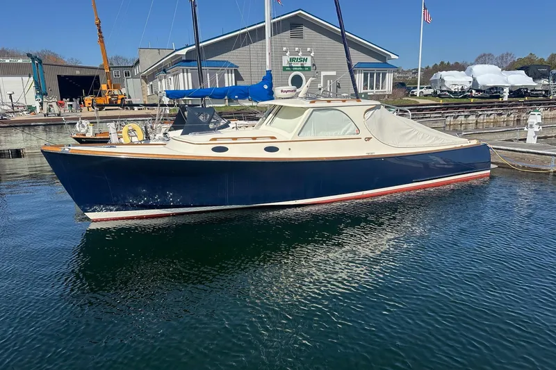 Slide: The Image of 1996 Hinckley Picnic Boat 36 Classic docked at a marina, featuring a sleek navy hull. - 33