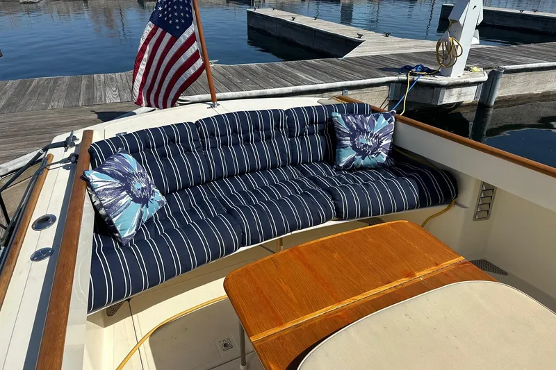 Slide: The Image of 1996 Hinckley Picnic Boat 36 Classic with striped seating and floral cushions at a marina. - 6