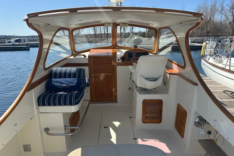 Slide: The Image of 1996 Hinckley Picnic Boat 36 Classic interior with helm and seating, docked by the water. - 7