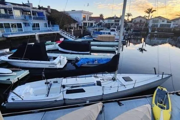Slide: The Image of Sailboats docked in a serene marina at sunset, featuring a 1983 Cape Bay Fast 40. - 14