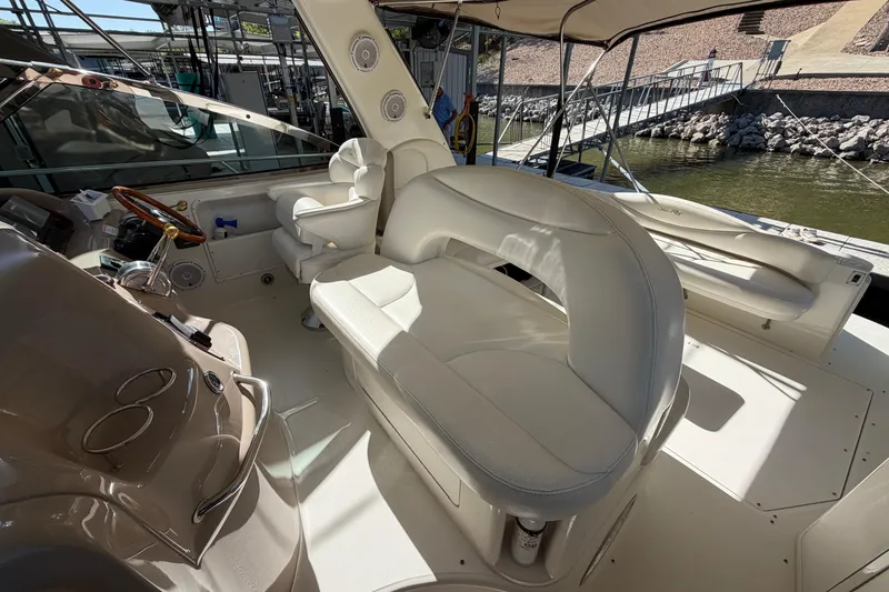Slide: The Image of 2000 Sea Ray 410 Sundancer cockpit with white seating and helm, docked by the water. - 15