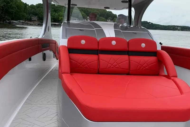 Slide: The Image of 2019 Mystic Powerboats M4200 with luxurious red seating on a serene lake. - 20