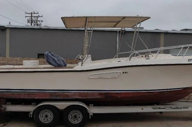 The Image of 1991 Mako 286 boat on trailer, parked outdoors near industrial building. - 0