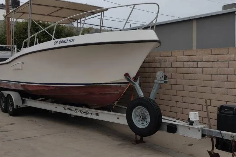 Slide: The Image of 1991 Mako 286 boat on trailer, parked beside a brick wall. - 2
