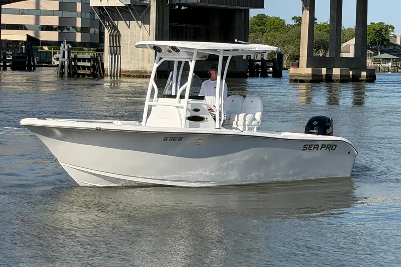 Slide: The Image of 2018 Sea Pro 219 Center Console boat cruising on calm waters near a bridge. - 4