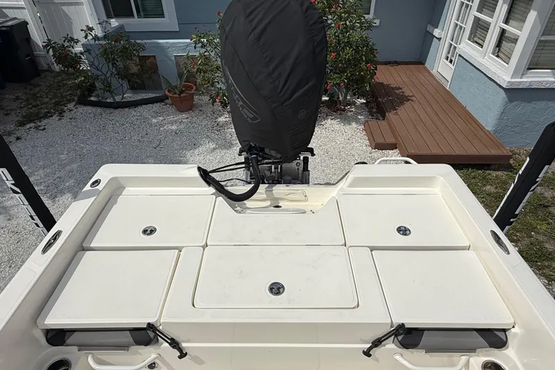 Slide: The Image of 2023 Skeeter SX230 boat deck with covered outboard motor, in a garden setting. - 12