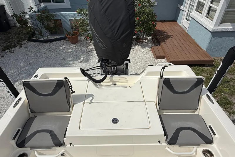 Slide: The Image of 2023 Skeeter SX230 boat with cushioned seating and covered motor, docked near a house. - 13