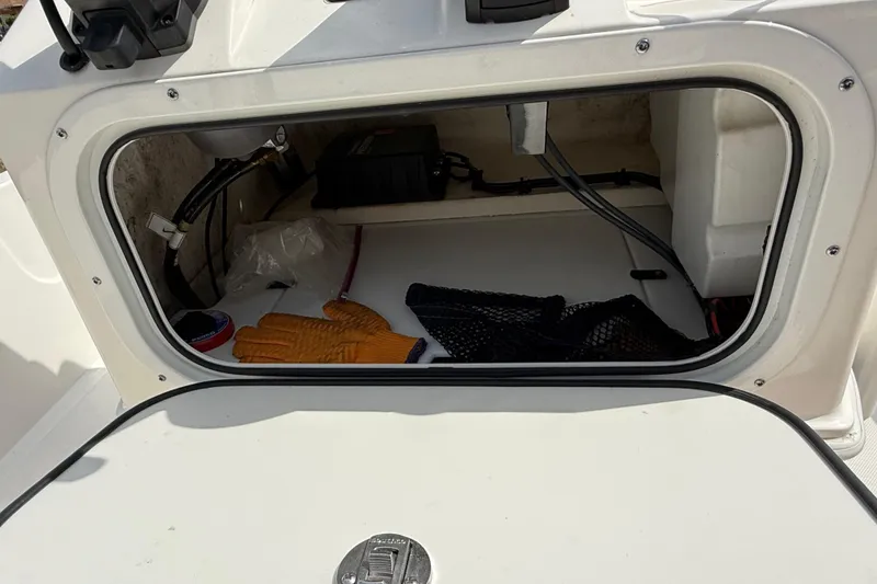 Slide: The Image of Storage compartment of 2023 Skeeter SX230 boat with gloves and netting inside. - 24