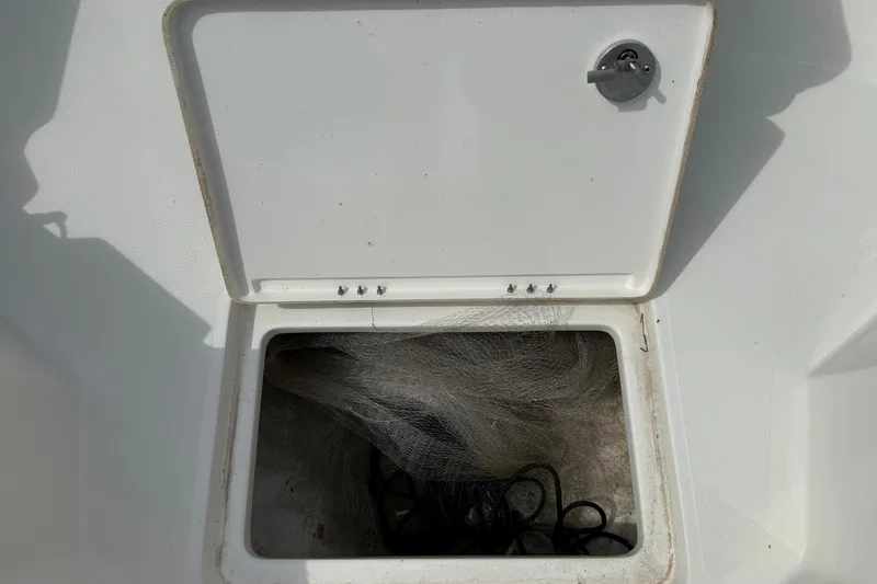 Slide: The Image of Open storage compartment on 2023 Skeeter SX230 boat, containing fishing net and rope. - 35