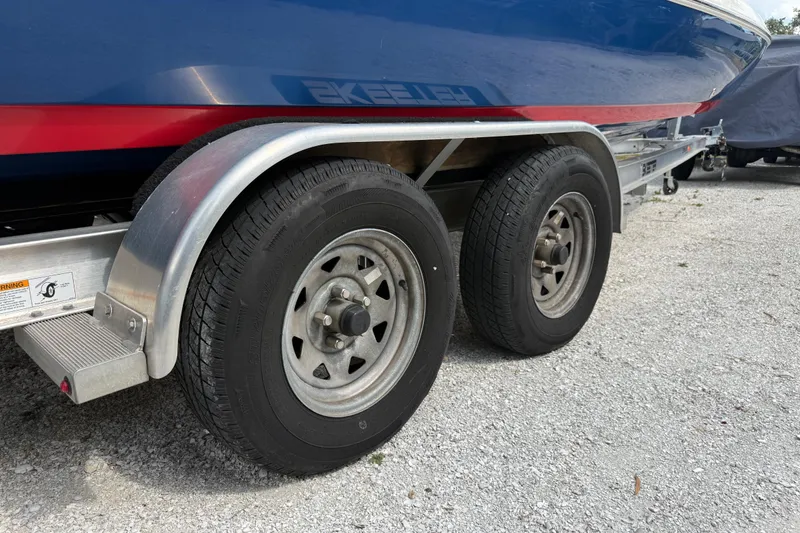 Slide: The Image of Trailer wheels of a 2023 Skeeter SX230 boat on gravel surface. - 36