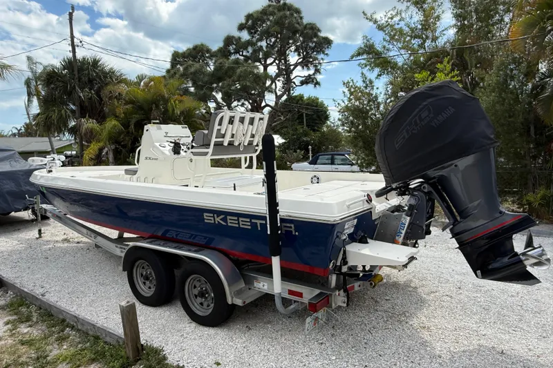 Slide: The Image of 2023 Skeeter SX230 boat on trailer, parked outdoors with Yamaha engine cover. - 4