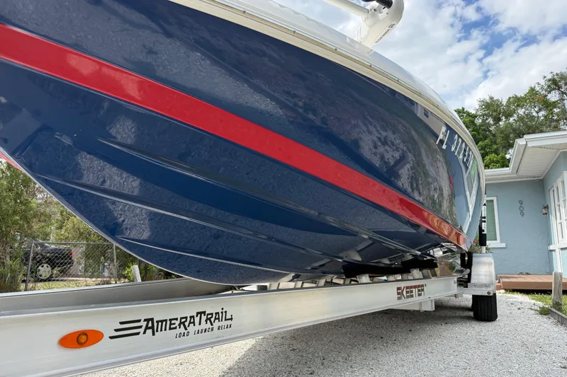 Slide: The Image of 2023 Skeeter SX230 boat on AmeraTrail trailer, blue with red stripe, parked outdoors. - 5