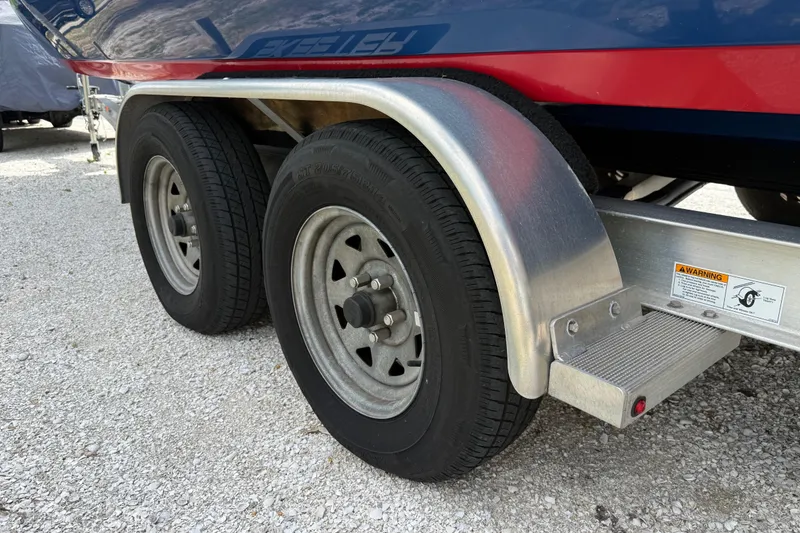 Slide: The Image of Trailer wheels of a 2023 Skeeter SX230 boat on gravel surface. - 8