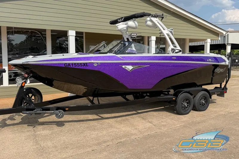 Slide: The Image of 2022 Tigé Z3 boat in vibrant purple and black on a trailer, parked outside a building. - 18