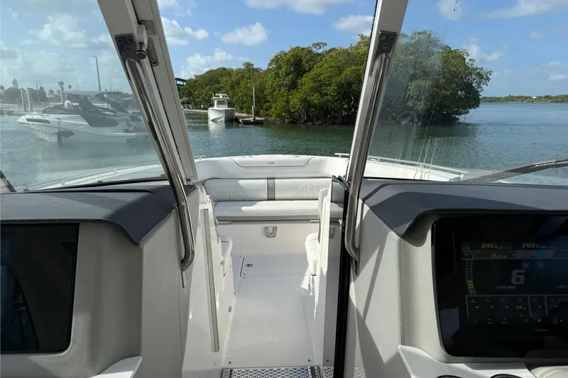 Slide: The Image of 2023 Regal LX36 boat interior with dashboard view, navigating calm waters near lush greenery. - 13