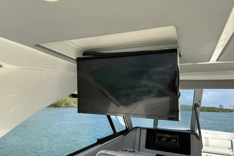 Slide: The Image of 2023 Regal LX36 boat interior with mounted flat-screen TV and scenic water view. - 16