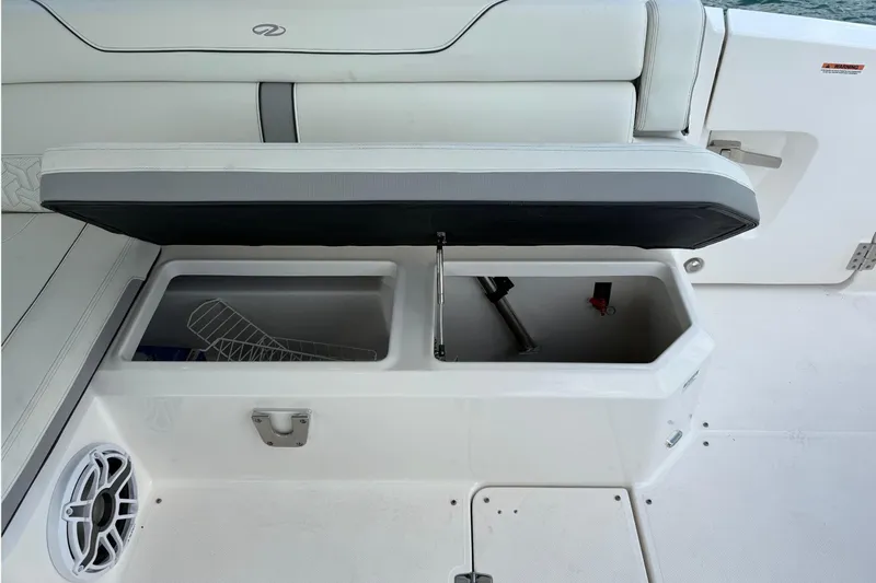 Slide: The Image of 2023 Regal LX36 boat storage compartment with open lid, showcasing interior space and speaker. - 23