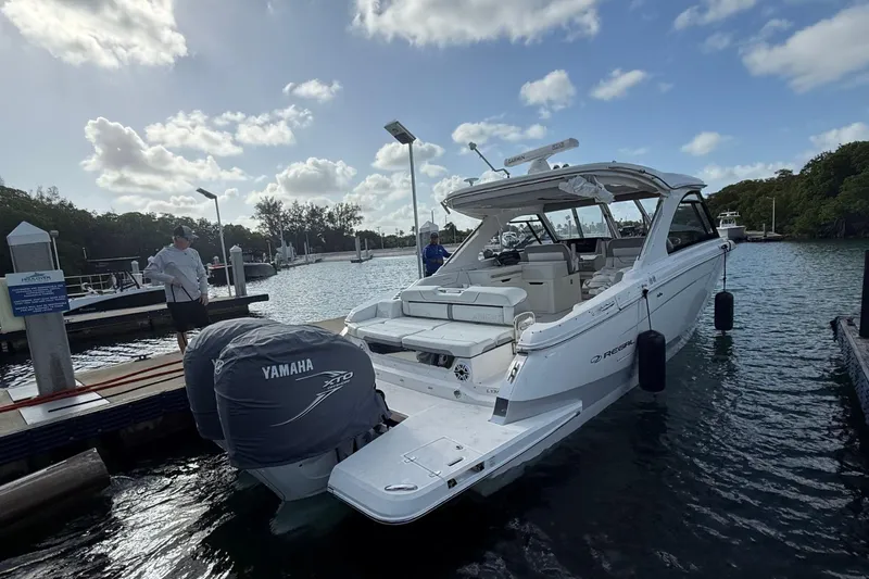 Slide: The Image of 2023 Regal LX36 boat docked with Yamaha engine, under a partly cloudy sky. - 3