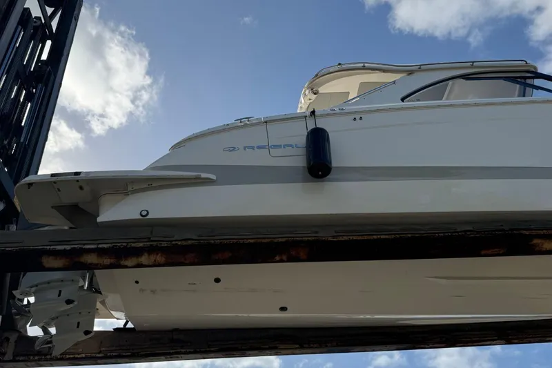 Slide: The Image of 2023 Regal LX36 boat on lift against blue sky background. - 30