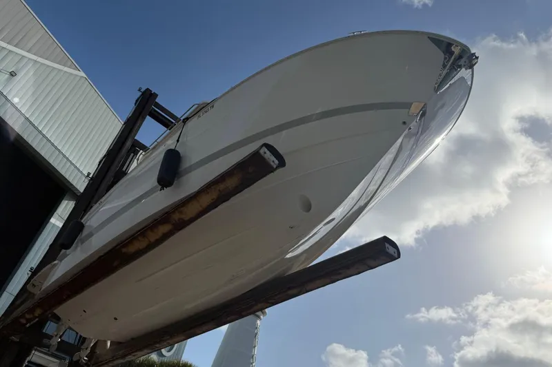Slide: The Image of 2023 Regal LX36 boat lifted in marina, under a bright sky. - 31