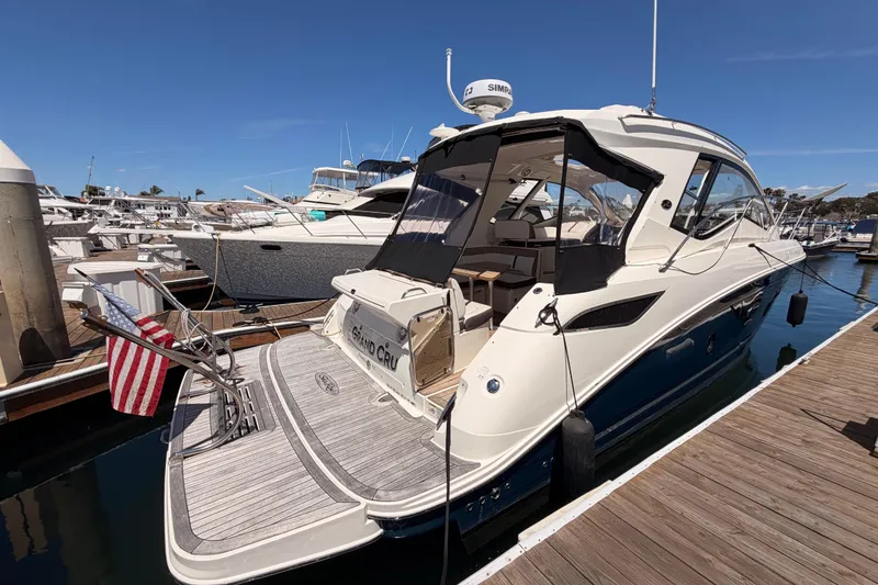Slide: The Image of 2018 Sea Ray Sundancer 350 Coupe docked at marina, rear view with American flag. - 2