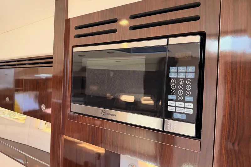 Slide: The Image of Microwave in 2018 Sea Ray Sundancer 350 Coupe yacht kitchen, featuring sleek wood paneling. - 45